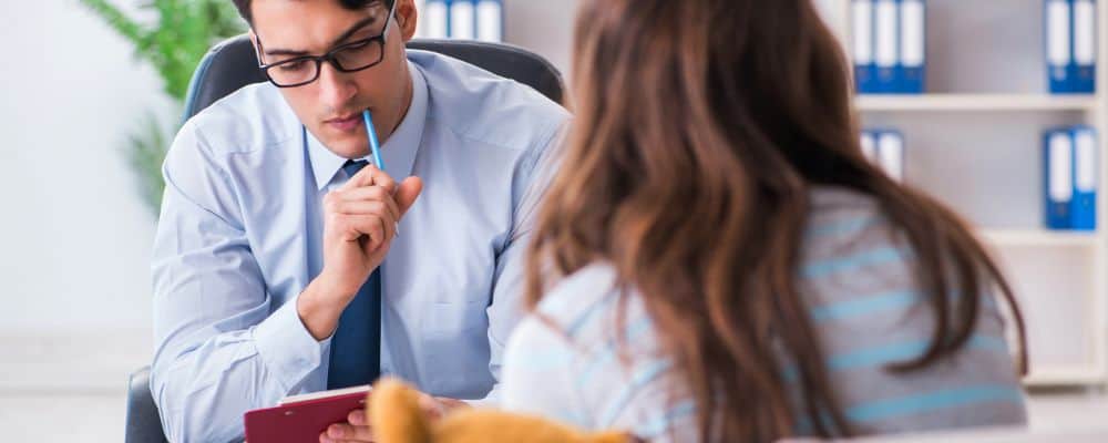 Do kogo po pomoc - psycholog, psychoterapeuta czy psychiatra? - psychiatra słucha uważnie swojej pacjentki, kt&oacute;ra siedzi naprzeciw niego - psychoterapeuta Wrocław Marita Woźny