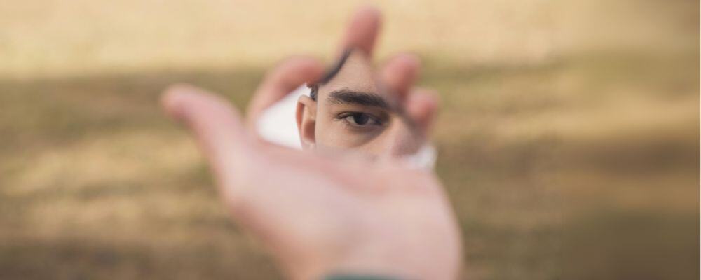 Jak dzieciństwo wpływa na rodzicielstwo? - osoba DDA przegląda się w pękniętym lustrze - psychoterapia Marita Woźny