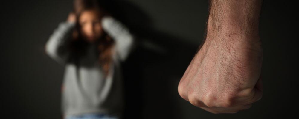 Przemoc domowa i przemoc psychiczna wobec dzieci &ndash; jak ją rozpoznać i przerwać? - dziecko w tle siedzi przestraszone, przed nim zaciśnięta pięść opiekuna - blog Marita Woźny