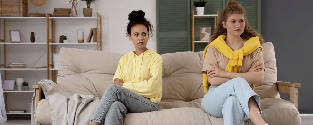 Dlaczego ciągle trafiam na niewłaściwe osoby w relacjach koleżeńskich i przyjaźniach? - dwie koleżanki siedzą na kanapie, między nimi jest konflikt, o kt&oacute;rym nie rozmawiają - blog Marita Woźny