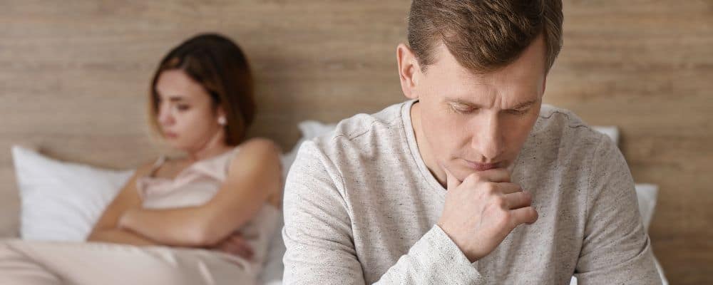 Grafika artykułu "Partner nie chce rozmawiać? Jak przerwać ciche dni w związku" przedstawiająca parę siedzącą na ł&oacute;żku w milczeniu - Marita Woźny psychoterapia